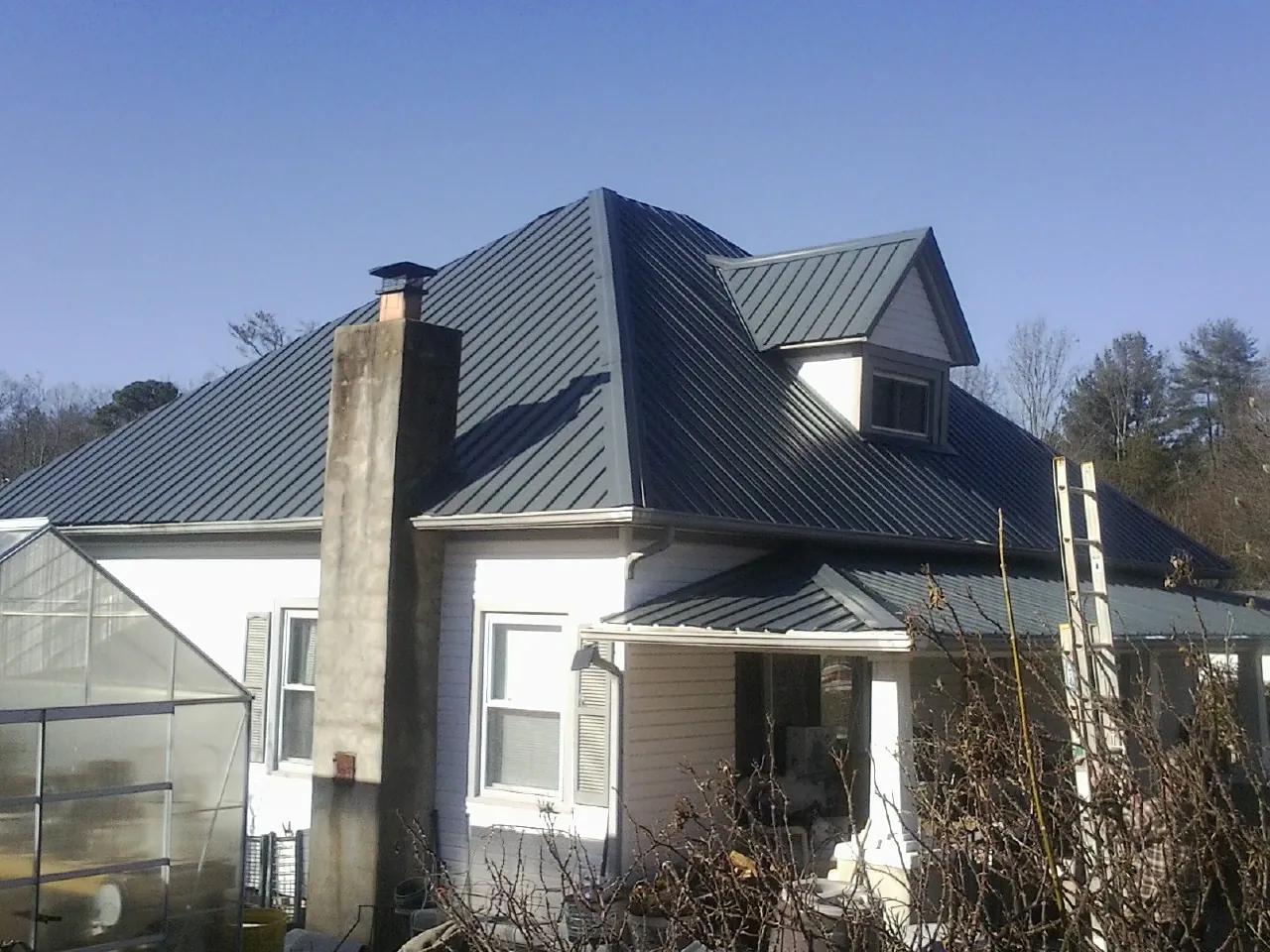 Dark blue standing seam metal roof on a white farmhouse with dormer — Slate & Tile Roof Repair by Roofing Brothers in Mount Laguna