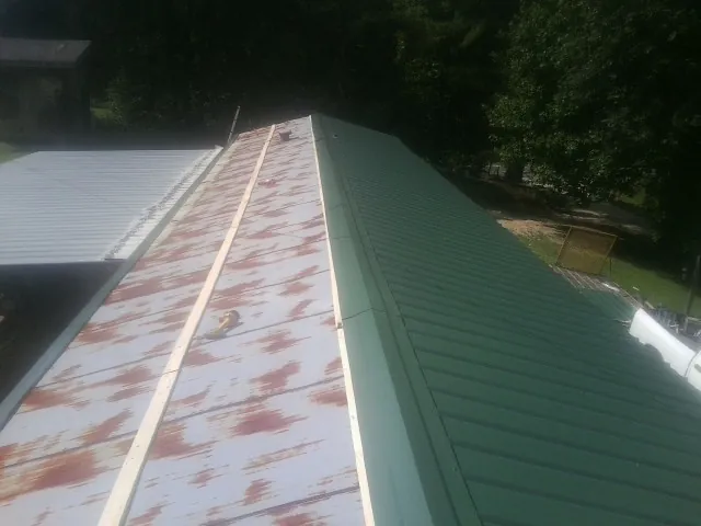 Old rusted panels beside newly installed green metal roofing — Wind Damage Roof Repair by Roofing Brothers in Mount Laguna