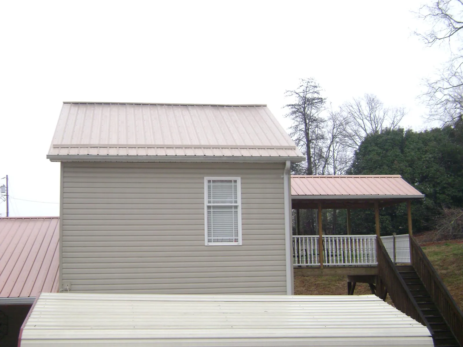 Tan metal roofs on a two story addition and attached porch, from a Roof Replacement job in Mount Laguna